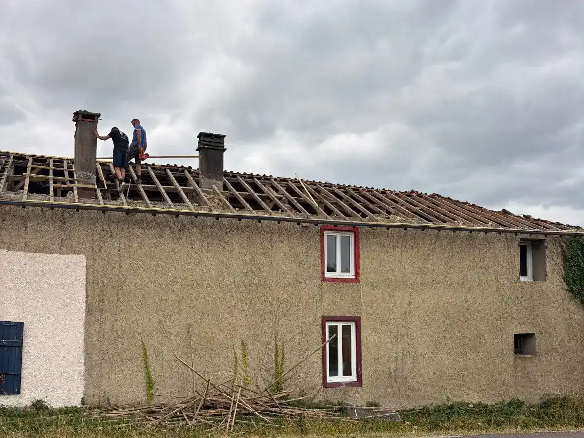 Toiture déposée et charpente à nu sur une maison de bourg béarnaise, vue depuis la route